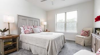 Furnished model bedroom with 9ft ceilings, ceiling fan, carpet and window at The Retreat at Fairhope Village in Fairhope, AL